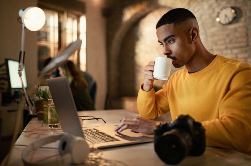 A young photographer planning his business at a laptop, camera on the desk