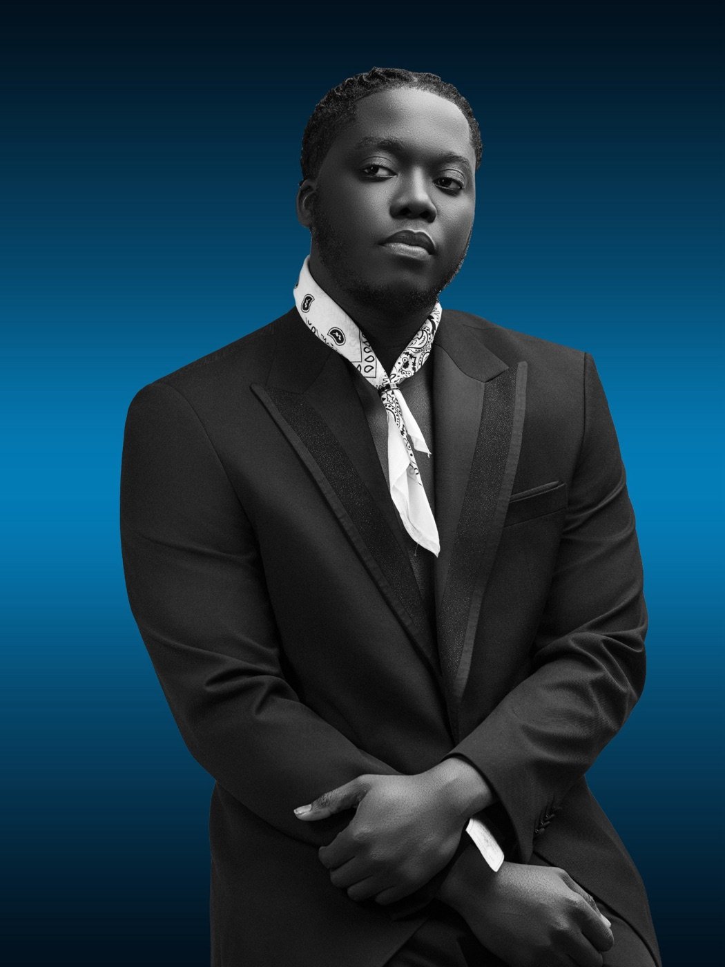 Francisco Vilton in a black suit and white bandana on a blue background